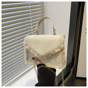 Détail du sac à franges crème avec bandoulière chaîne dorée et rabat en enveloppe