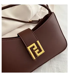 Detailed close-up of dark brown leather crescent bag with golden square buckle