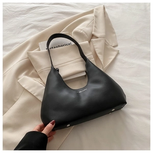 Detail of black faux leather crescent hobo bag with white text and protective metal feet