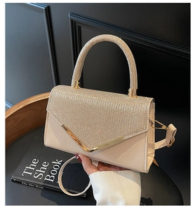 Detail of elegant beige crossbody bag featuring diamond-encrusted handle and V-shaped gold trim