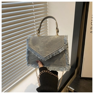 Détail du sac à bandoulière en denim avec bords effilochés et chaîne dorée chic