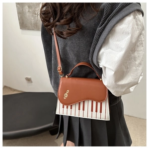 Detail of creative piano crossbody bag with G clef hardware and piano key pattern