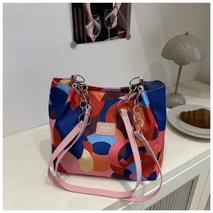 Detail of colorful geometric tote bag featuring pink leather strap and silver chain accent
