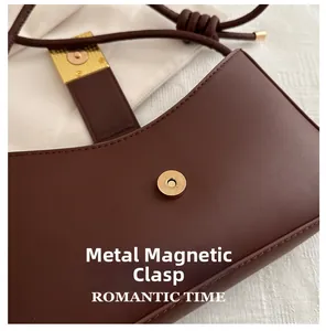 Close-up of golden hardware magnetic buckle on dark brown leather square handbag