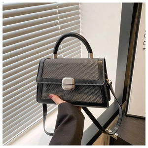 Détail d'un sac à main tressé gris avec garniture en cuir noir et boucle en métal