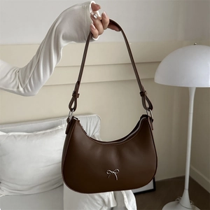 Detail of a brown hobo bag featuring a silver bow metal piece and smooth leather texture