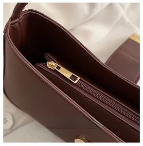 Detail of premium golden metal zipper and smooth dark brown leather on the crescent bag