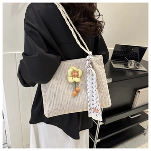 Detail of beige woven tote bag with yellow yarn flower and decorative silk scarf accessory