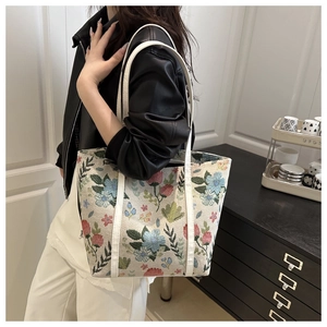 Detailed close-up of a vintage floral tote bag with embroidered patterns and white straps