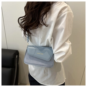 Light blue crossbody bag featuring woven texture and glossy patent leather flap