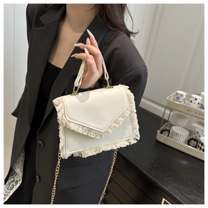 Détail du petit sac beige avec bordure à franges et bandoulière en chaîne dorée