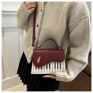 Detail of piano keyboard design and golden music note on a retro crossbody bag