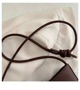 Detail of dark brown leather handle with golden metal tips and decorative knots