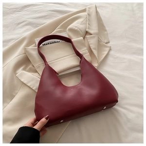 Detailed view of dark red leather crescent bag on a blazer with bottom metal rivets