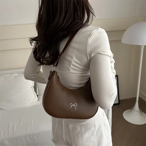 Close-up of brown leather hobo bag with a silver bow buckle and adjustable strap