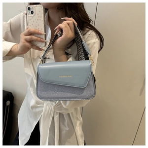 Detail of light blue patchwork shoulder bag with geometric strap and gold hardware