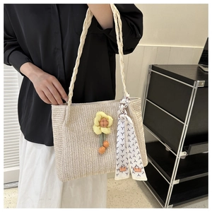 Detail of beige straw tote bag with sunflower charm and colorful scarf handle