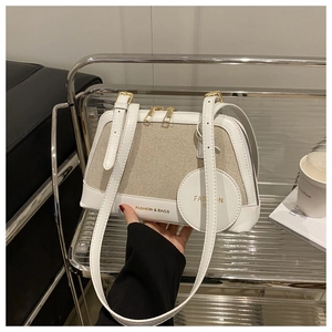 Detail showing white leather and canvas patchwork bag with double gold zippers and brand logo