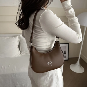 Dark brown crescent shoulder bag with silver bow accent and adjustable strap