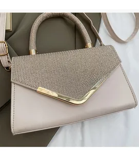 Detail of glittery flap cover and golden V-shaped metal trim on beige crossbody bag