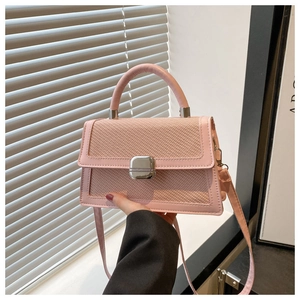Détail d'un sac bandoulière rose tissé avec boucle argentée et finitions en cuir