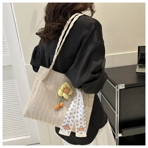 Detail of beige woven straw tote bag with sunflower charm and decorative scarf