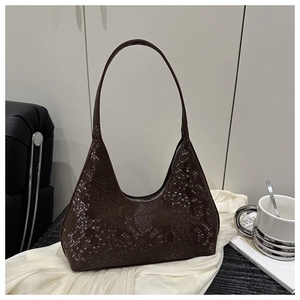 Macro detail of dark brown snakeskin embossed leather on a vintage crescent bag