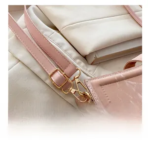Detail of pink baguette bag showing gold hardware hooks and adjustable shoulder strap