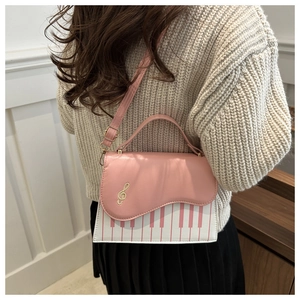 Detail of piano key pattern and treble clef embroidery on pink and white square bag