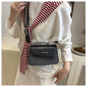 Close-up of contrast crossbody bag featuring woven texture and geometric patterned strap