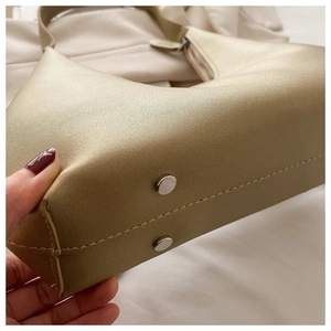Macro shot of champagne gold crescent bag with silver base studs and bold stitching