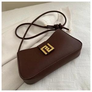 Detail of dark brown baguette bag featuring a gold geometric clasp and knotted strap
