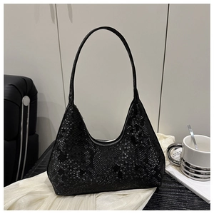 Detail of black snake pattern hobo bag on a white fabric surface in a minimalist interior