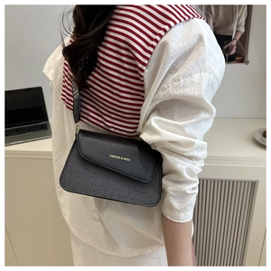 Detail of crossbody bag with black woven texture and geometric patterned wide strap