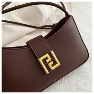 Detail of premium brown leather crossbody bag with elegant gold metal buckle closure