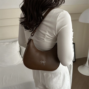 Close-up of brown leather hobo bag with a silver metallic bow and zipper detail