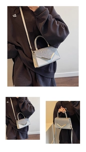 Detail view of mini sequin handbag with V-shaped gold metal trim and silver glitter accents