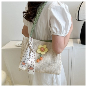Detail of woven straw tote bag with green strap and decorative yellow flower embellishment