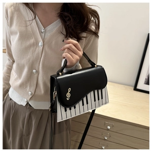 Detail view of piano key pattern and gold clef charm on a black and white handbag