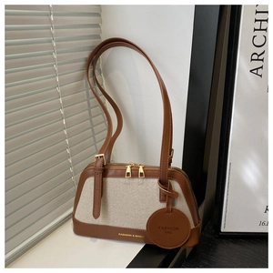 Detail of canvas and leather patchwork tote with double zippers and fashion charm