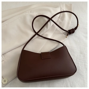 Detail of dark brown leather handbag featuring knotted shoulder strap and gold hardware