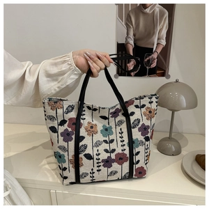 Close-up of floral jacquard fabric and black leather handles on a large tote bag
