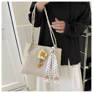 Detail of woven straw tote with sunflower charm and black and white printed scarf