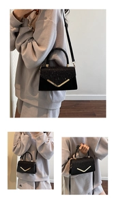 Detail view of black sequined crossbody bag with V-shaped gold metal trim and strap