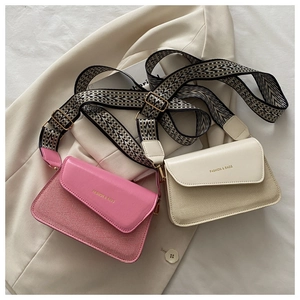Detail of color-block crossbody bag with wide geometric strap and gold lettering