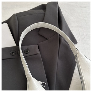 Detail shot of white embossed snake texture leather shoulder bag with silver zipper hardware