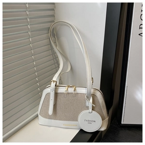 Detailed close-up of beige canvas patchwork tote with white leather trim and metal zippers