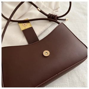 Detail view of smooth dark brown leather handbag with magnetic closure and gold accents