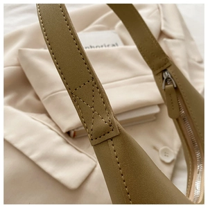 Close-up of olive green shoulder bag showing X-shaped reinforced stitching and zipper detail
