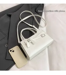 White mini square bag with bow detail and phone for size comparison, crossbody style